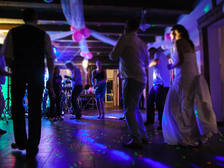 Večerný parket a hostia tancujúci pod svetelnými efektmi na svadobnej party
