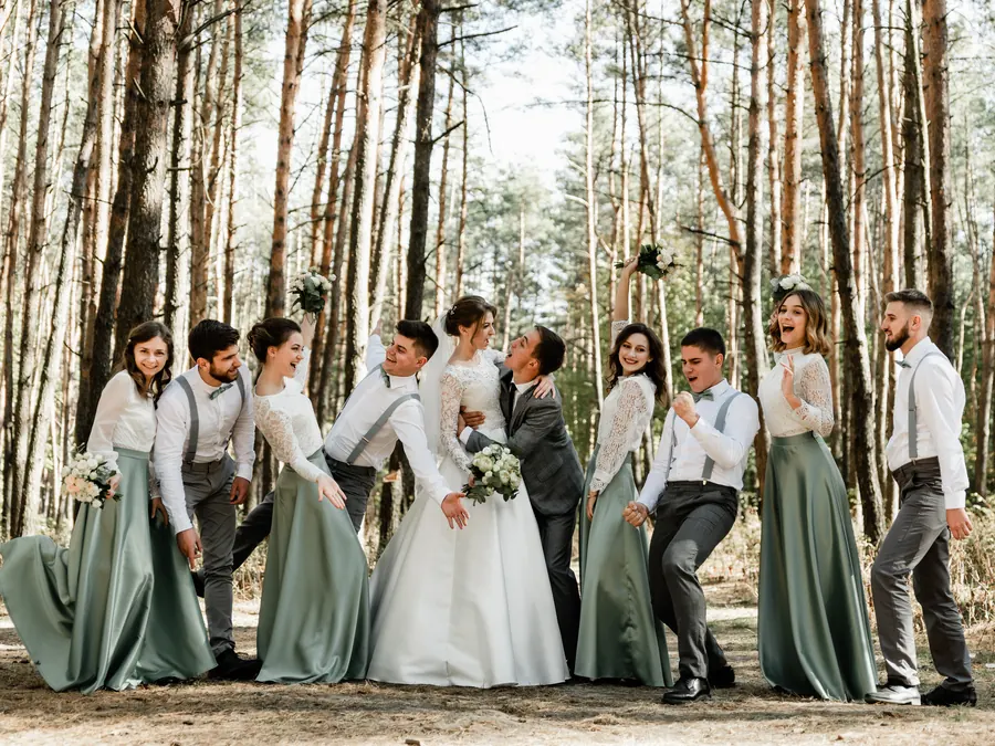 Svadobná partia a družičky smejúce sa v borovicovom háji